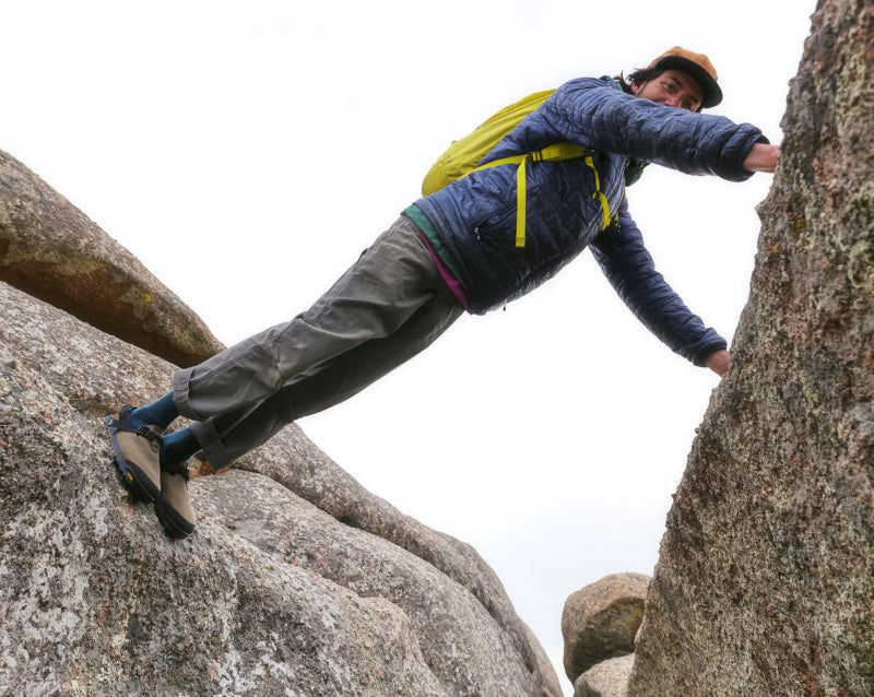 Person climbing a rocky mountain with a backpack