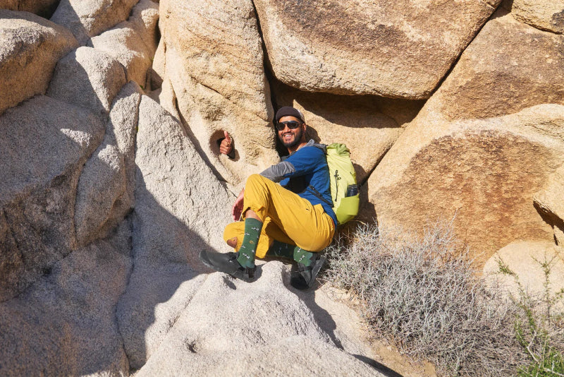 Person in outdoor gear sitting among large rocks with a backpack
