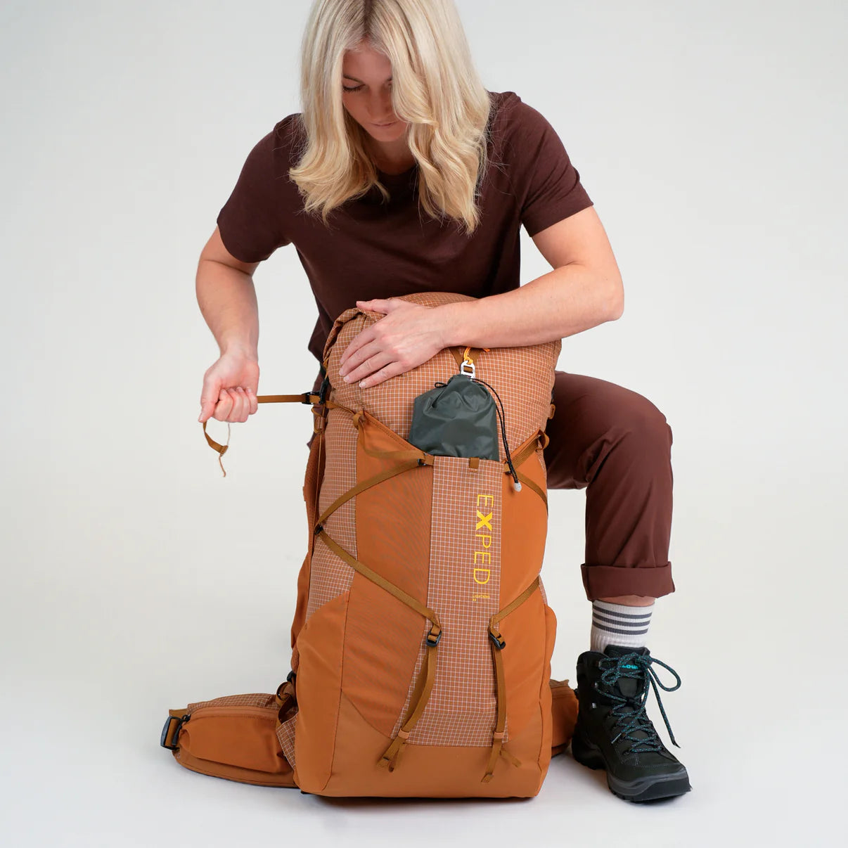 Person sitting with a large brown backpack on a white background