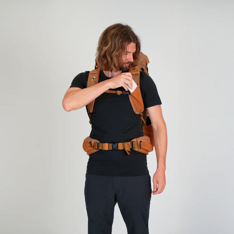 Man wearing a brown backpack on a plain background