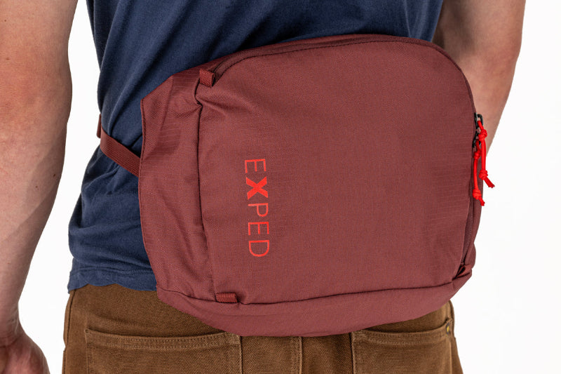 Brown bag with 'Exped' logo worn by a person on a white background