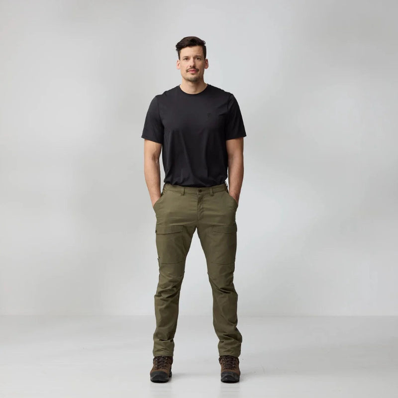Man wearing a black t-shirt and green pants on a white background