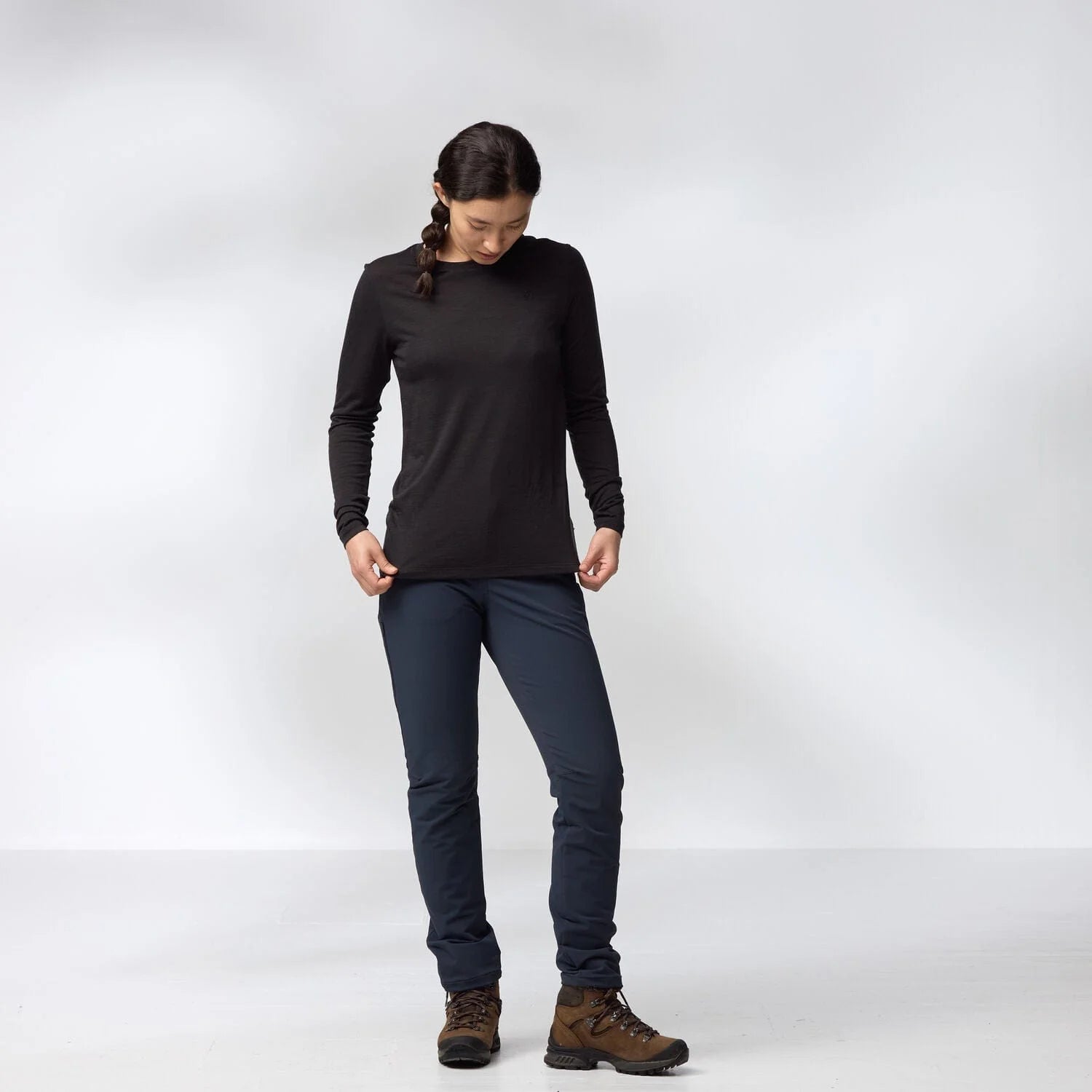 Person wearing a black long-sleeve top and dark pants on a white background