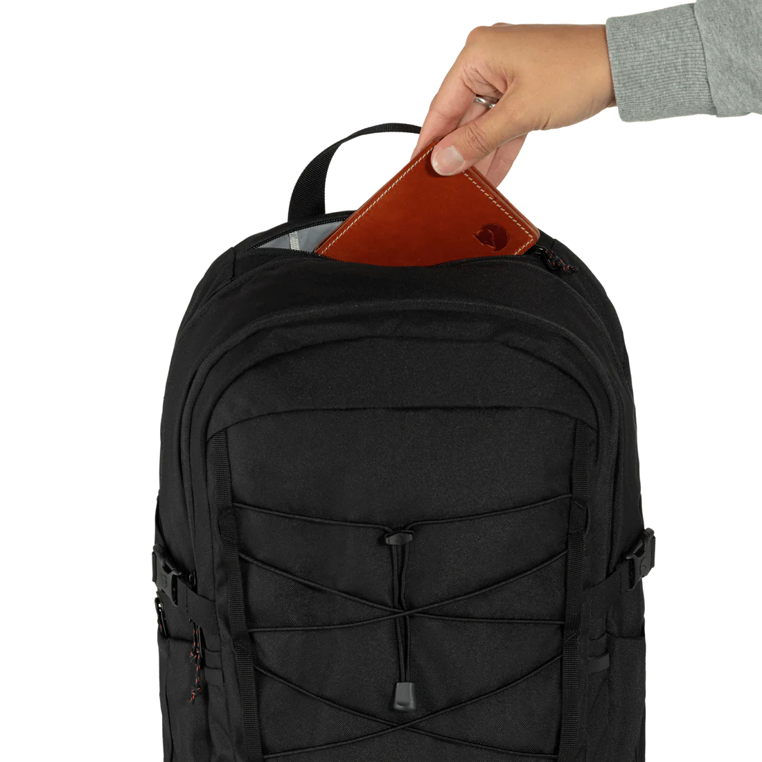 A lady pulling out a wallet from the small pocket on the top of the backpack