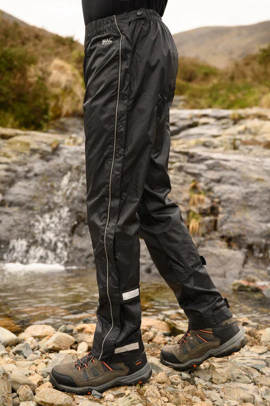 A person wearing full zip rain pants near a river