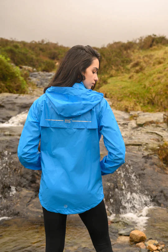 Woman with her back to us, standing in a river looking over her shoulder wearing blue mac in a sac rain jacket