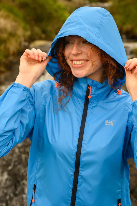 Woman wearing a blue rain jacket, holding the hood over her head