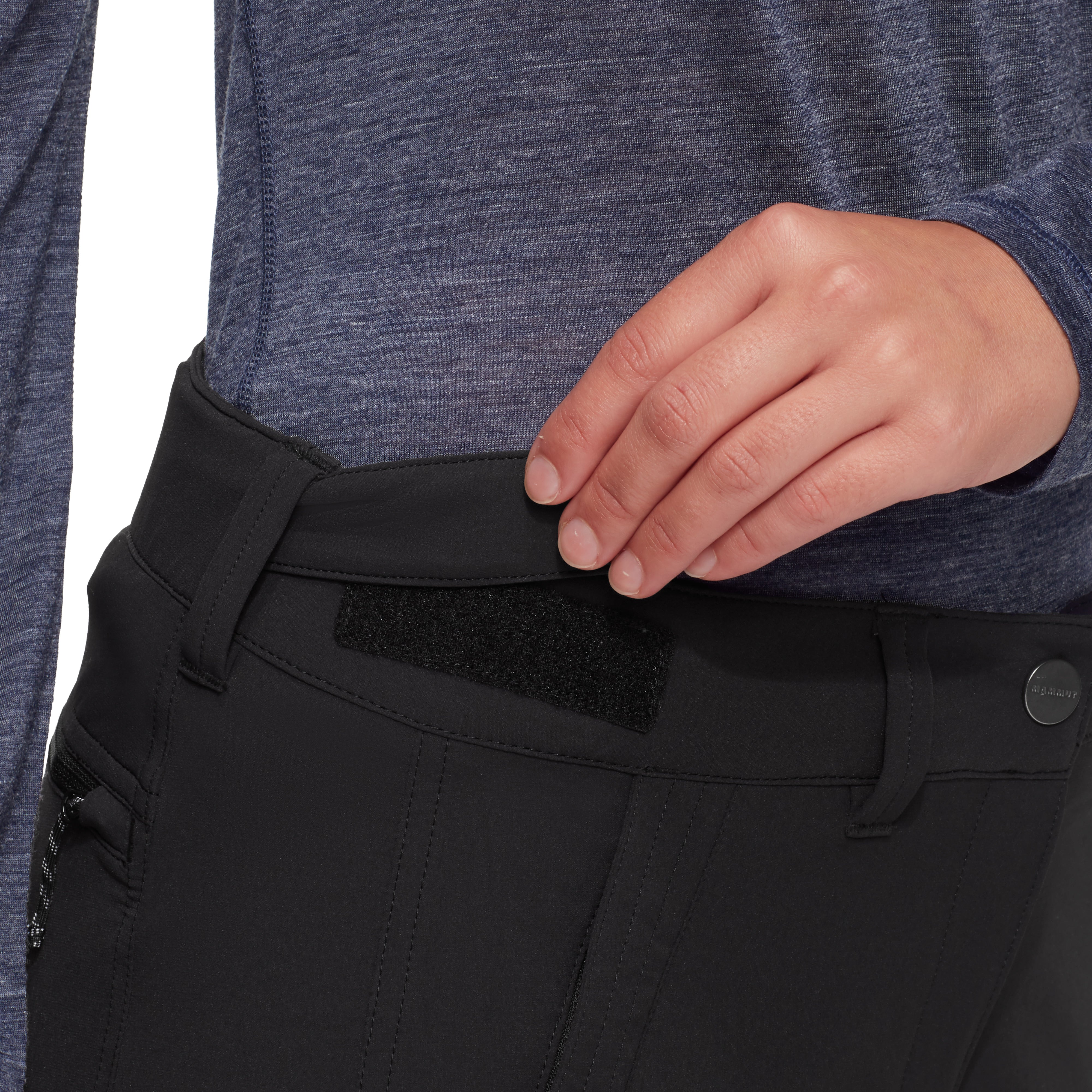 Person wearing black pants with a close-up of the waistband and a hand adjusting it.