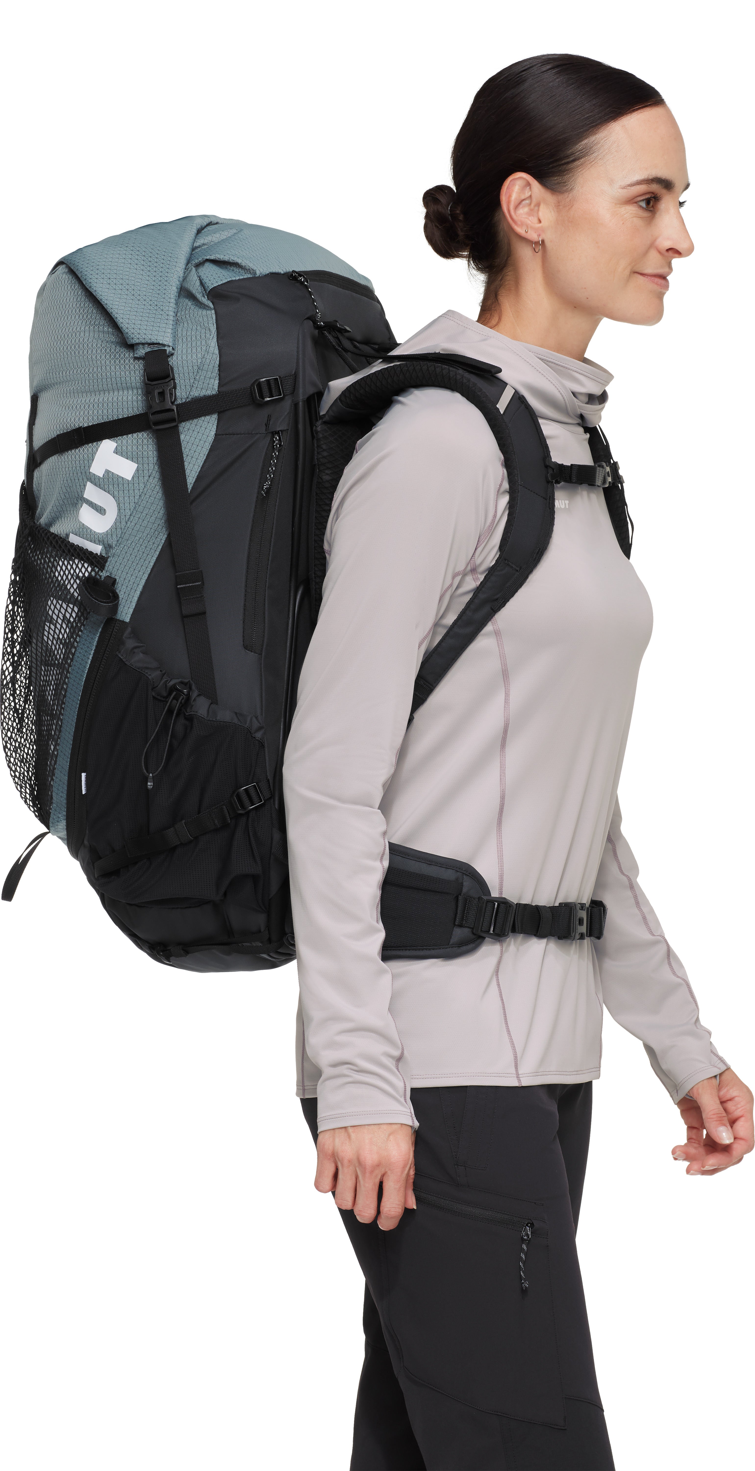 Woman wearing a large backpack with a visible brand logo on a white background