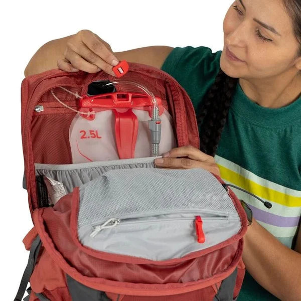 Person opening a red backpack with a water bladder inside