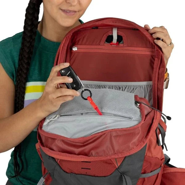 Person holding a red backpack with a clear view of its interior compartments.
