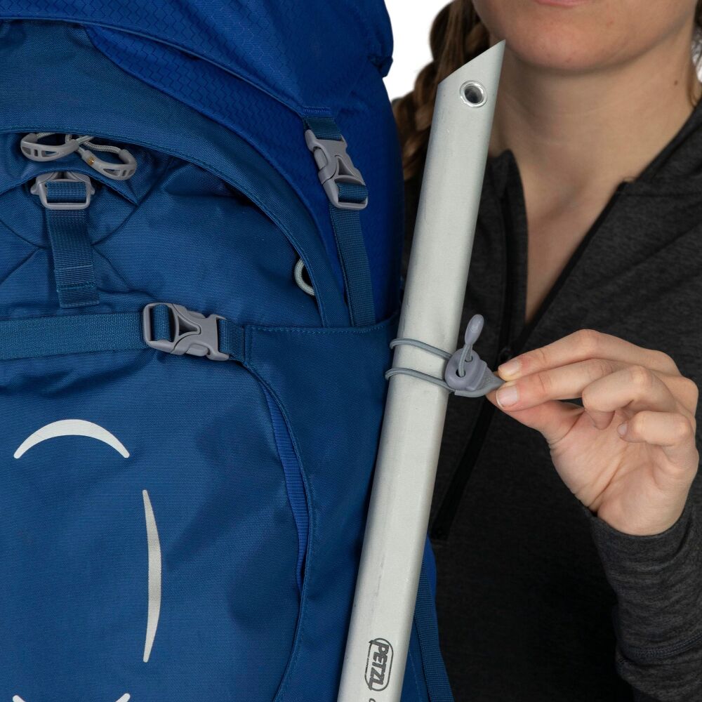 Person holding a white ski pole with a blue backpack in the background