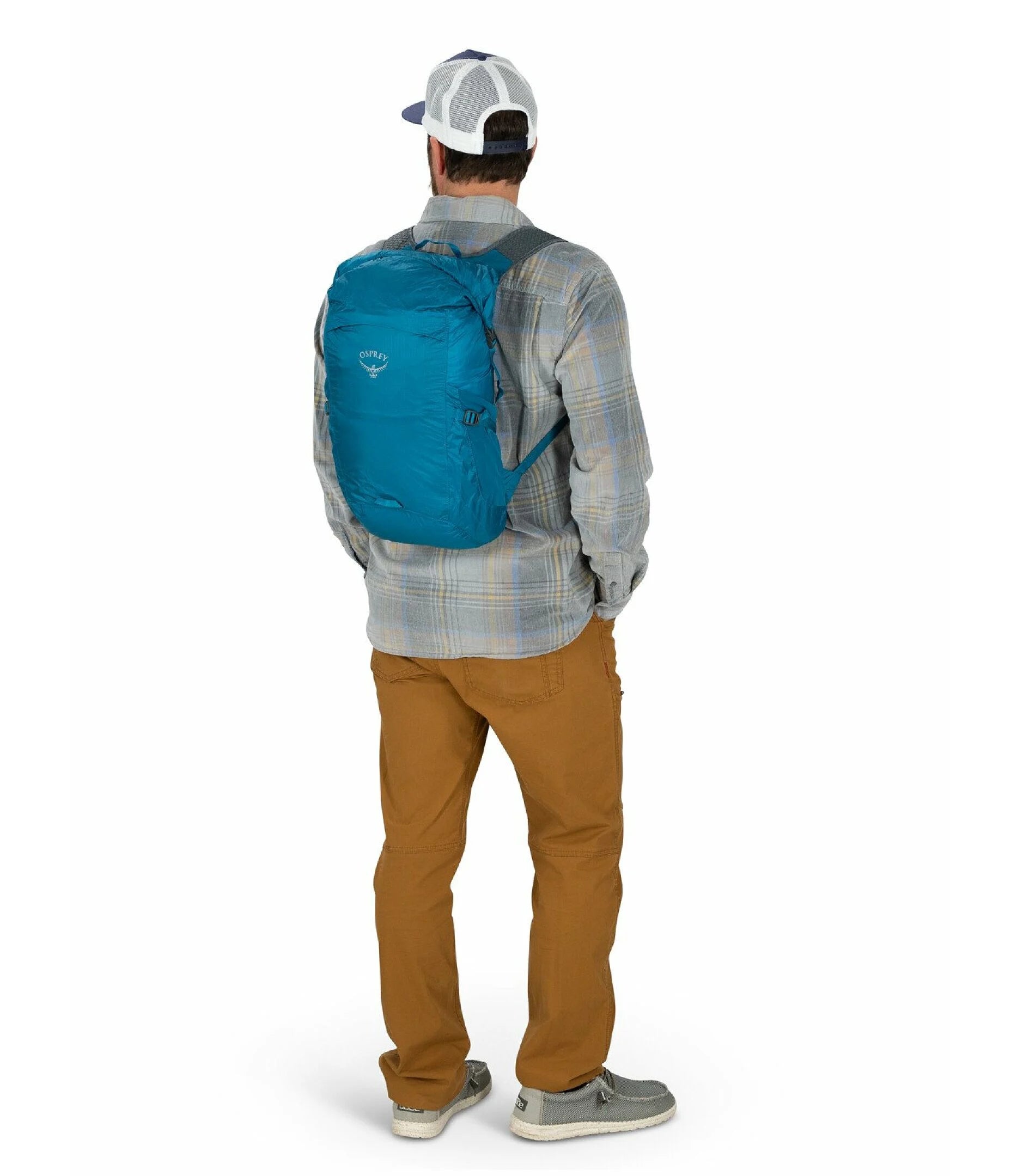 Person wearing a blue Osprey backpack and plaid shirt on a white background