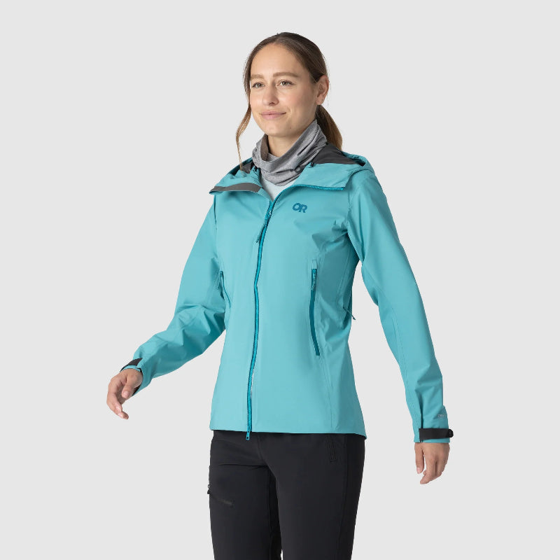 Woman wearing a turquoise jacket with a visible brand logo on a white background