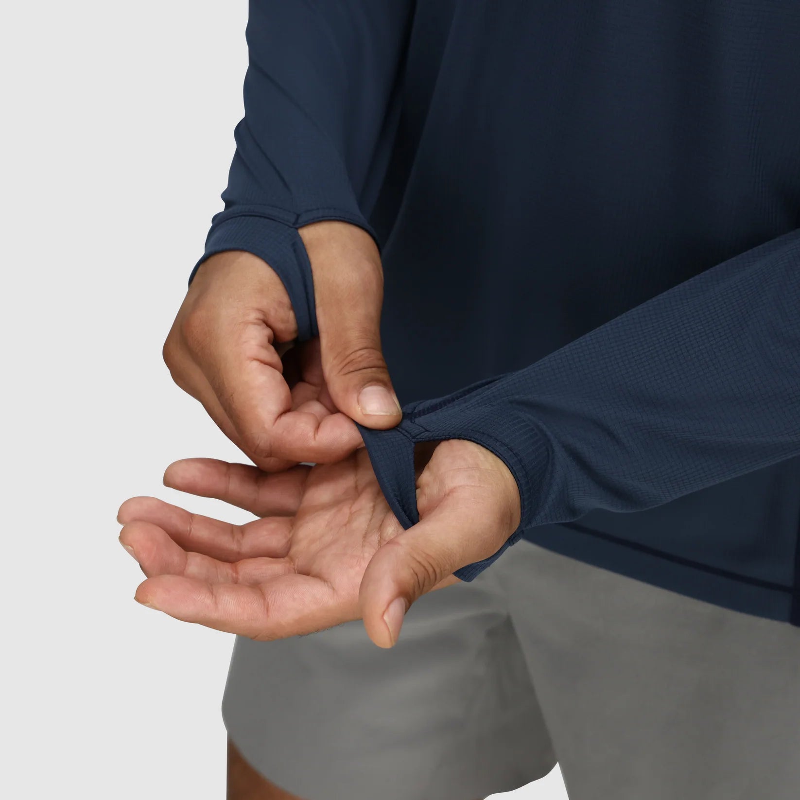 Person wearing a navy long-sleeve hiking shirt and gray hiking shorts, adjusting the sleeve.
