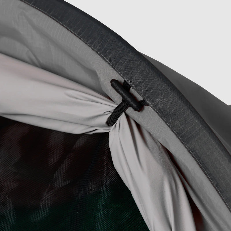 Close-up of a tent zipper with a black zipper pull on a gray background