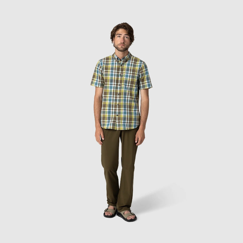 Man wearing a plaid shirt and brown pants on a white background