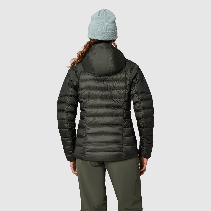 A woman shown from the back wearing a dark olive green hooded puffer jacket, olive green pants, and a light blue beanie against a light gray studio background.
