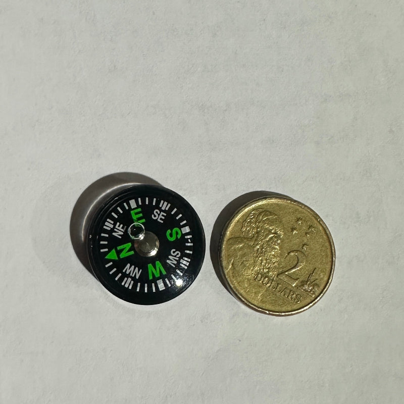 Small compass next to a coin for size comparison