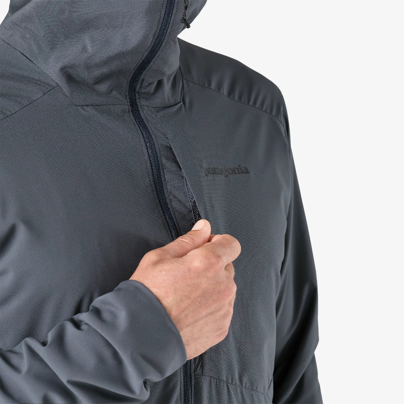 Close-up of a person wearing a gray jacket with a brand logo on a light gray background