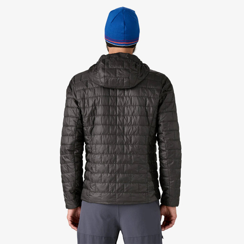Person wearing a dark gray quilted jacket and blue beanie on a white background