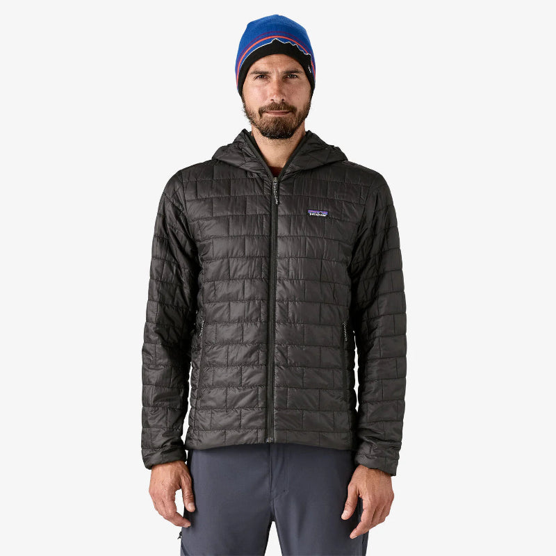 Man wearing a dark gray quilted jacket and blue beanie on a white background