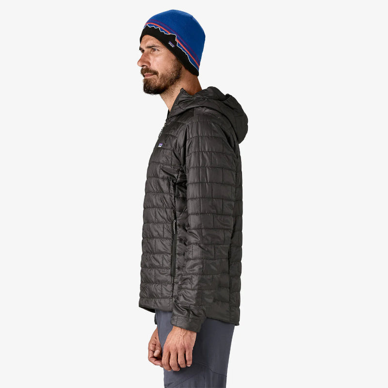 Man wearing a dark gray quilted jacket and blue beanie on a white background