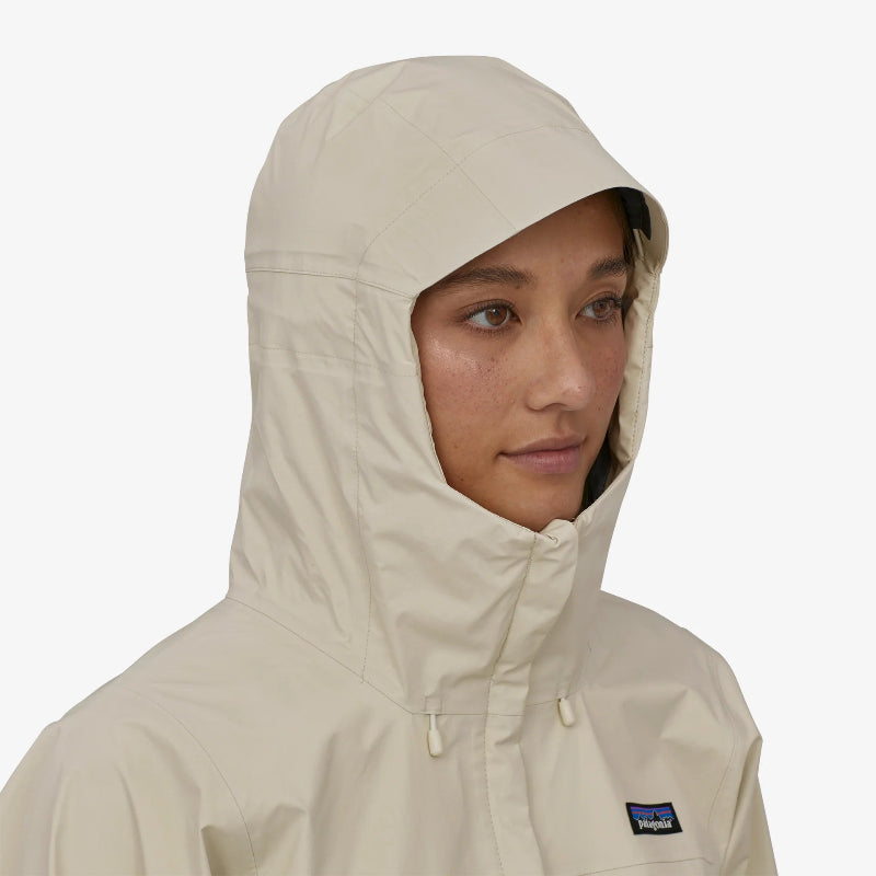 A woman wearing the Patagonia Women's Torrentshell 3L Rain Jacket in wool white with the hood up