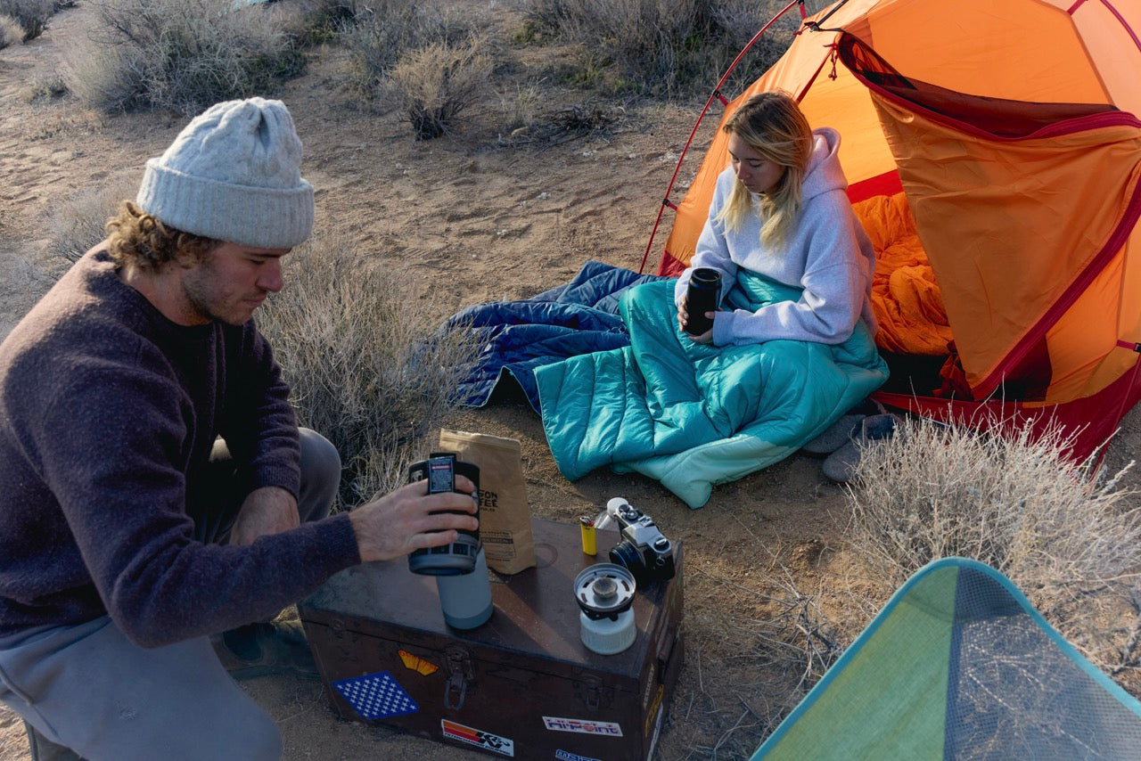 Two people camping in a desert setting with a 2 person tent and Jetboil Stove and Rumpl Waterproof Blanket