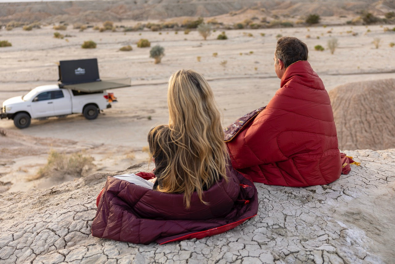 Two people sitting in a desert landscape in Australia with a rumpl waterproof travel blanket
