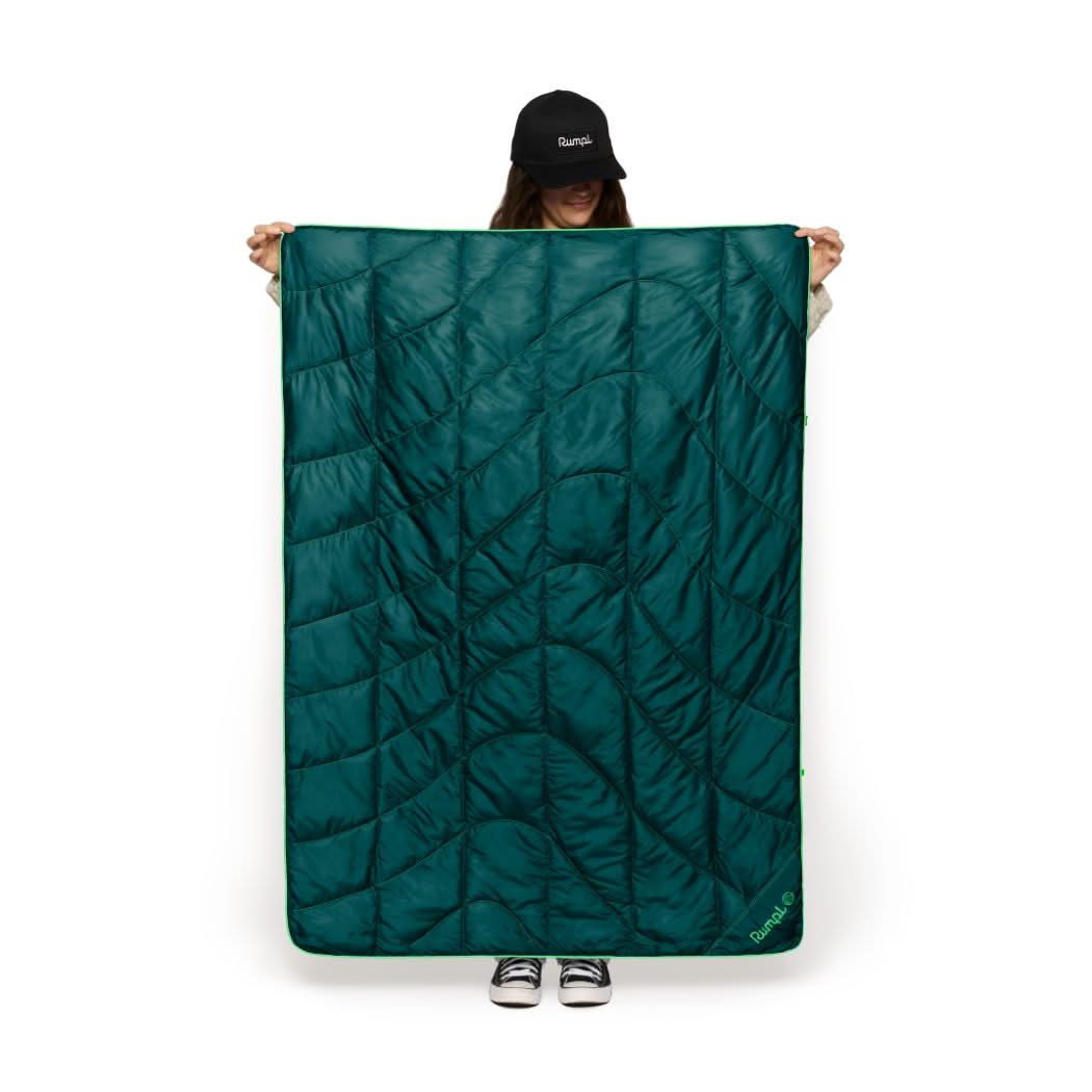 Woman holding up the Rumpl puffy travel blanket