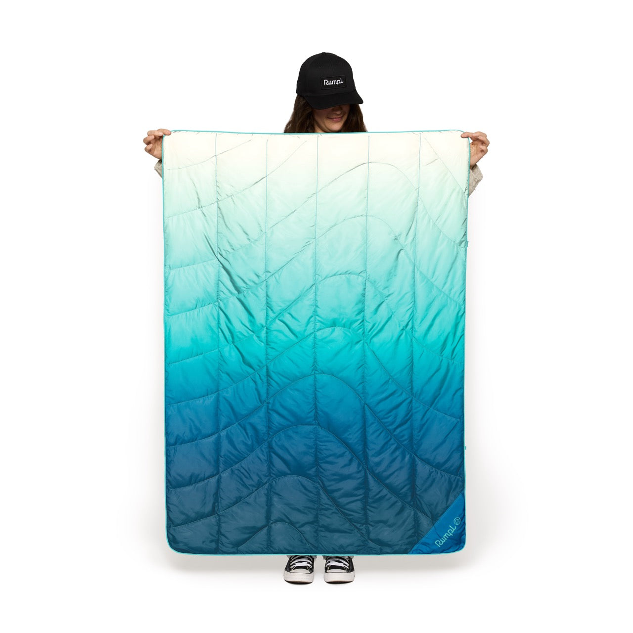 Person holding a large blue and green gradient waterproof blanket with a white background