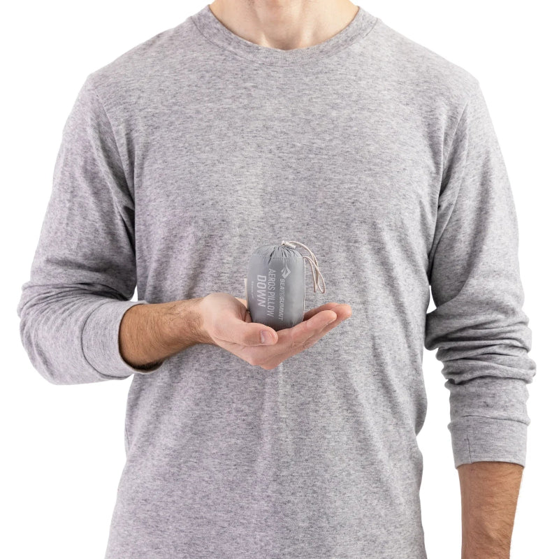 Person holding a pillow in a clear bag against a white background