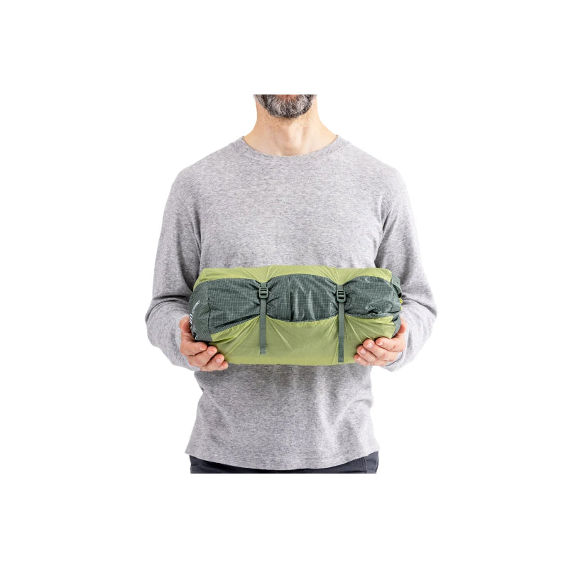 Person holding a green compression bag against a white background