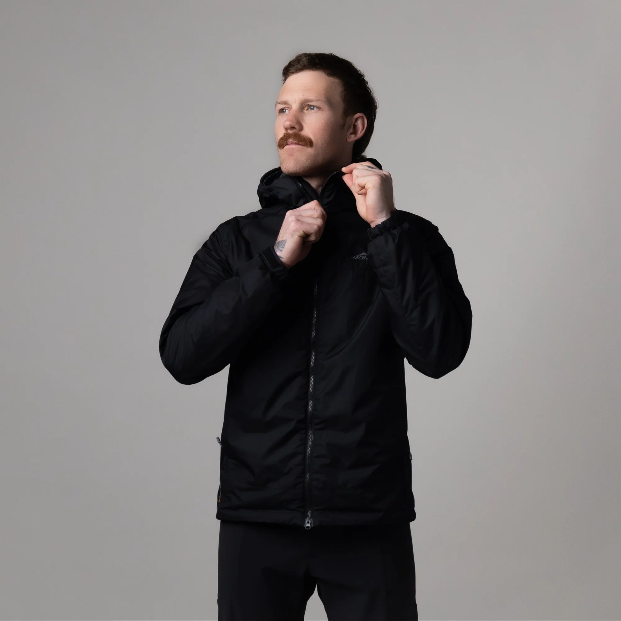 Man wearing a black jacket against a gray background