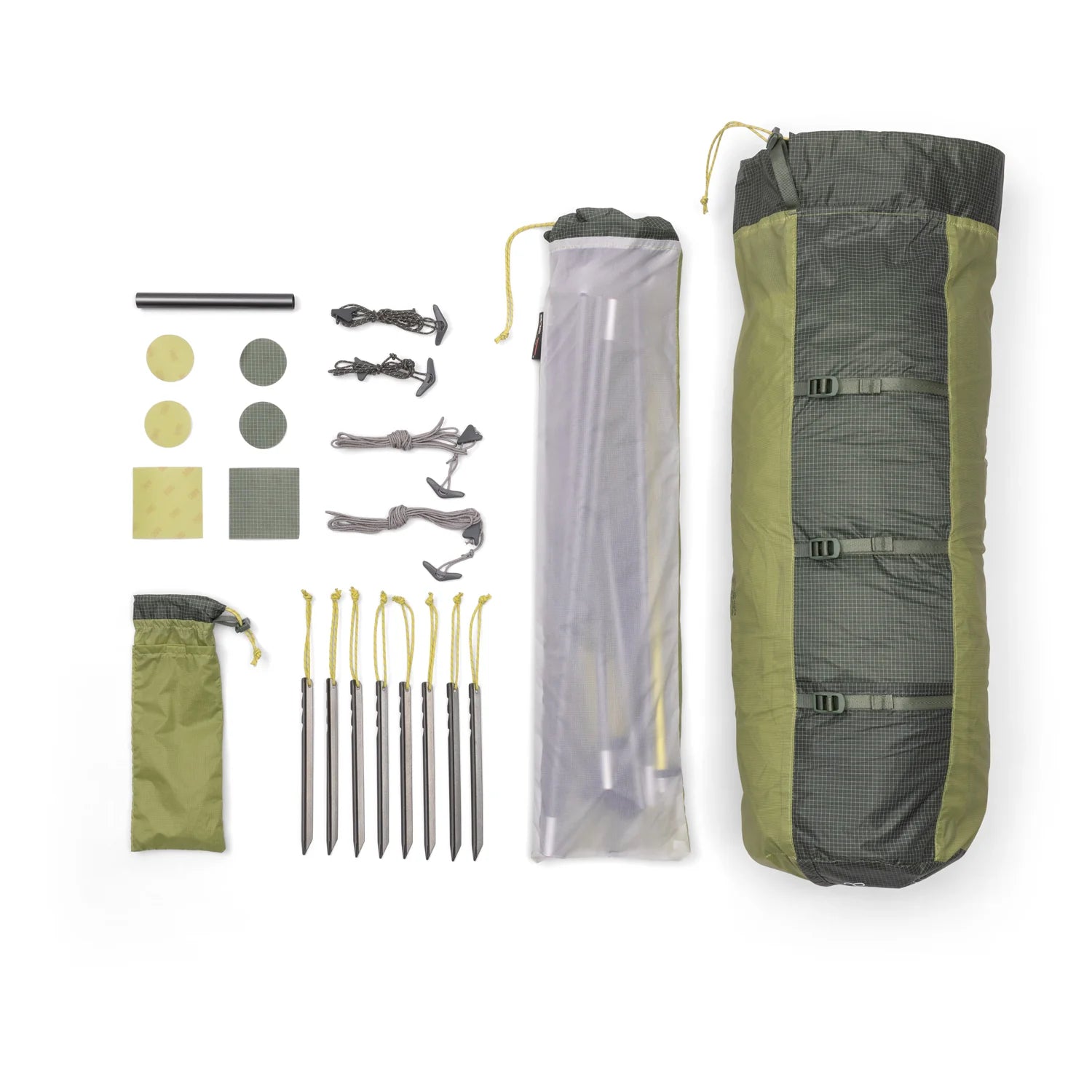 Flat lay of camping gear including a sleeping bag, tent stakes, and ropes on a white background