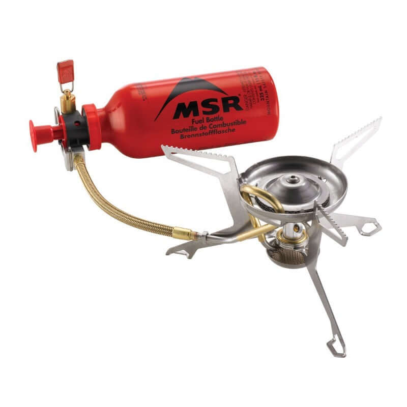 MSR Whisperlite International multi-fuel stove with a red fuel bottle, stainless steel body, and foldable design.